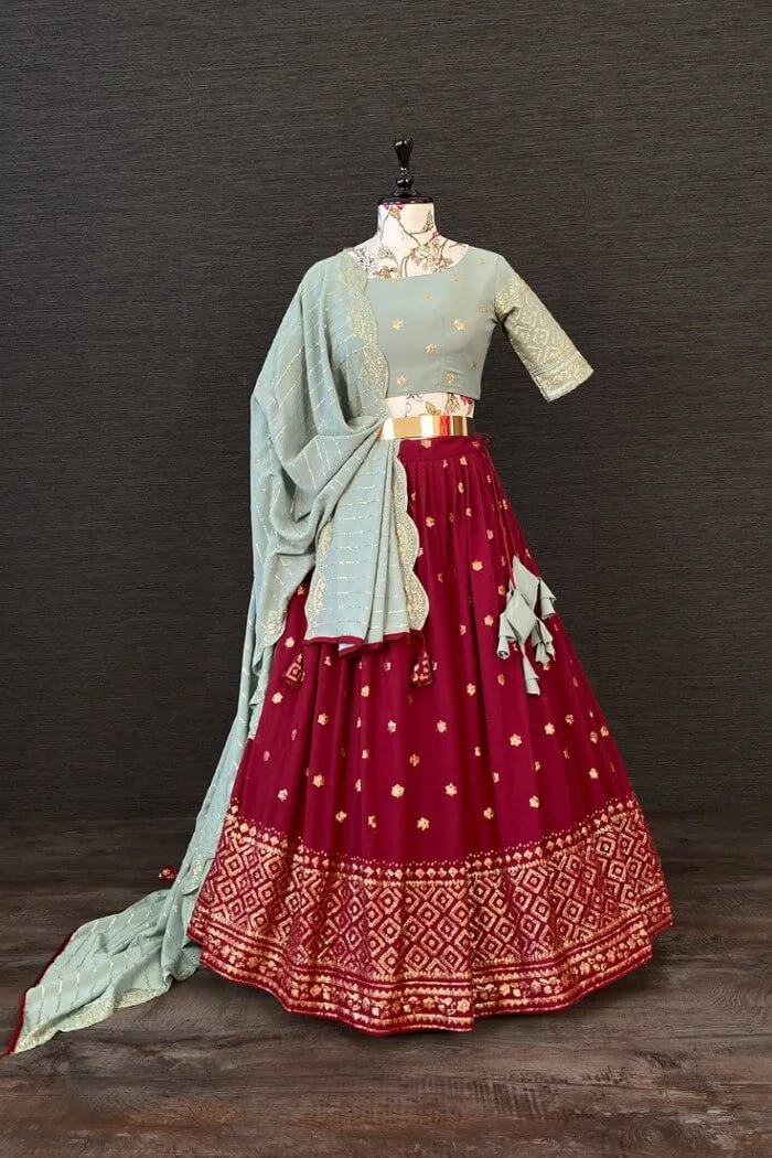 Mannequin in a maroon lehenga with gold embroidery, light blue blouse & dupatta, and elegant jewelry.