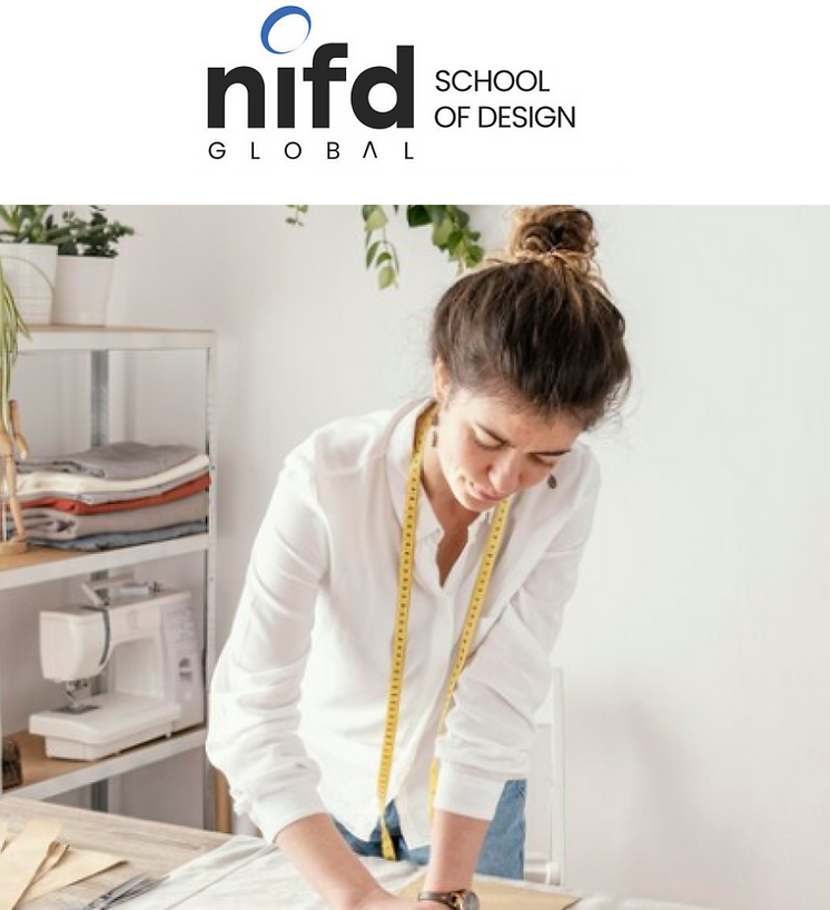 A woman in a white shirt with a yellow measuring tape works on a design project, with fabric shelves and a sewing machine. NIFD Global School of Design is at the top.